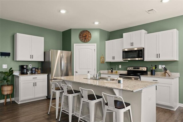 867 Starbuck Pkwy, Pendergrass, GA 30567 - kitchen featuring white cabinets, appliances with stainless steel finishes, a breakfast bar area, baseboards, and dark wood-style floors