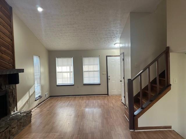 unfurnished living room with a fireplace, hardwood / wood-style floors, and a textured ceiling