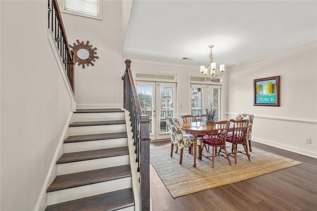 dining area with dark wood-type flooring, crown molding, and a notable chandelier