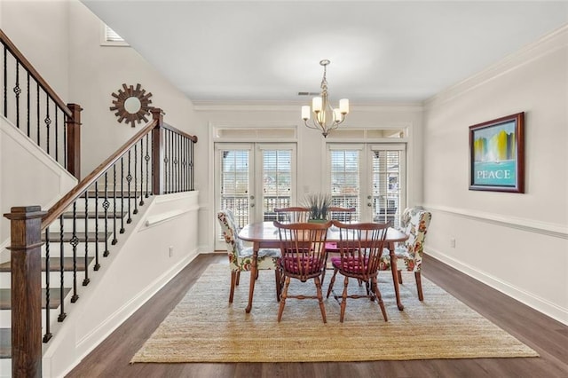 dining space featuring dark hardwood / wood-style flooring, crown molding, french doors, and a chandelier