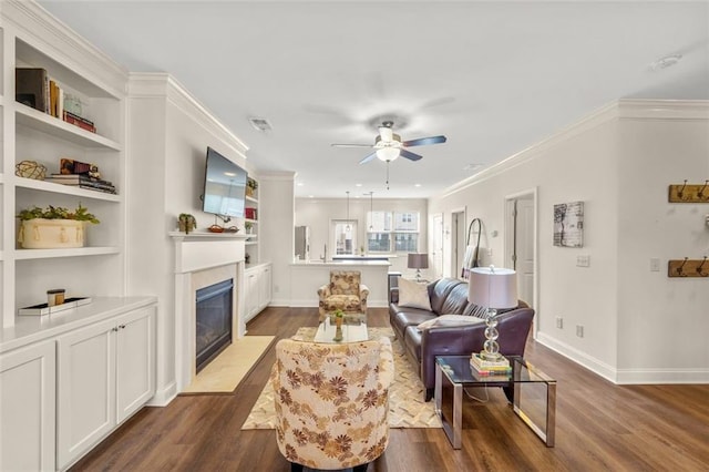 living room featuring crown molding, built in features, dark hardwood / wood-style floors, and ceiling fan