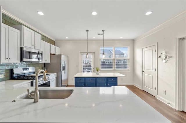 kitchen featuring blue cabinets, light stone counters, appliances with stainless steel finishes, pendant lighting, and white cabinets