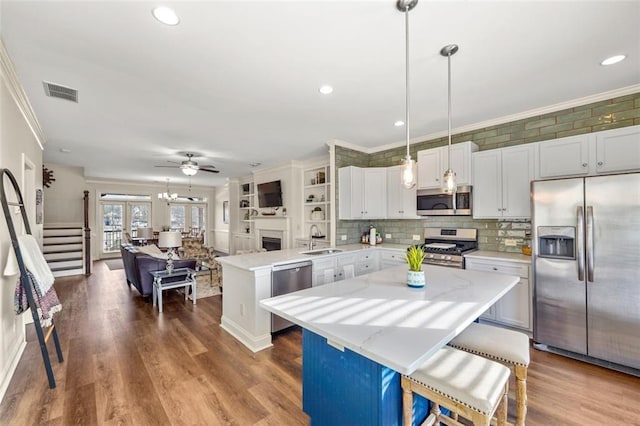 kitchen with a kitchen island, appliances with stainless steel finishes, a breakfast bar, decorative light fixtures, and kitchen peninsula