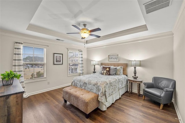 bedroom with crown molding, a tray ceiling, and dark wood-type flooring