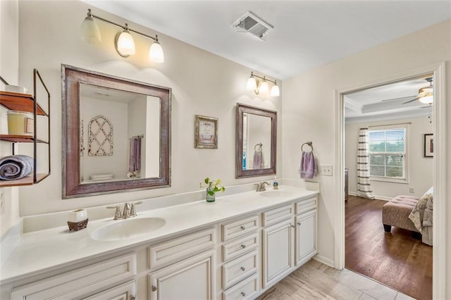 bathroom with vanity, ceiling fan, and a tray ceiling