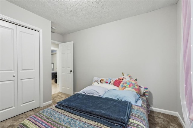 carpeted bedroom featuring a closet, a textured ceiling, and baseboards