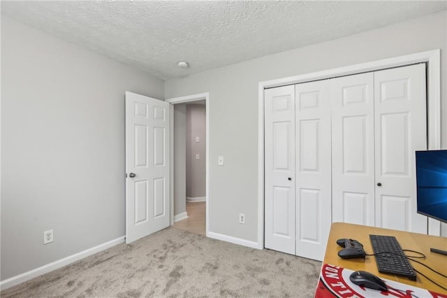 bedroom featuring a closet, baseboards, a textured ceiling, and carpet flooring