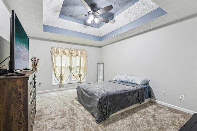 bedroom featuring a tray ceiling, carpet flooring, and baseboards