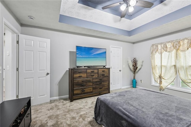 bedroom with a raised ceiling, a ceiling fan, baseboards, and carpet floors