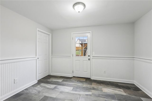 unfurnished room featuring a wainscoted wall