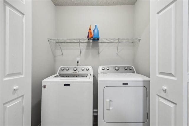 washroom with a textured ceiling, laundry area, and washer and clothes dryer