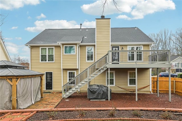 back of house with a deck, stairs, fence, a gazebo, and a chimney