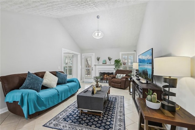 living room featuring light tile patterned floors, a textured ceiling, a lit fireplace, and high vaulted ceiling