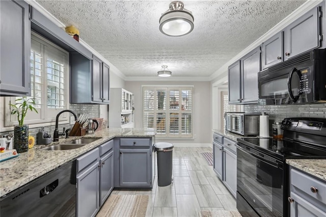 kitchen featuring gray cabinetry, ornamental molding, plenty of natural light, black appliances, and a sink