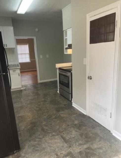 kitchen featuring stainless steel range with electric cooktop, black fridge, and white cabinets