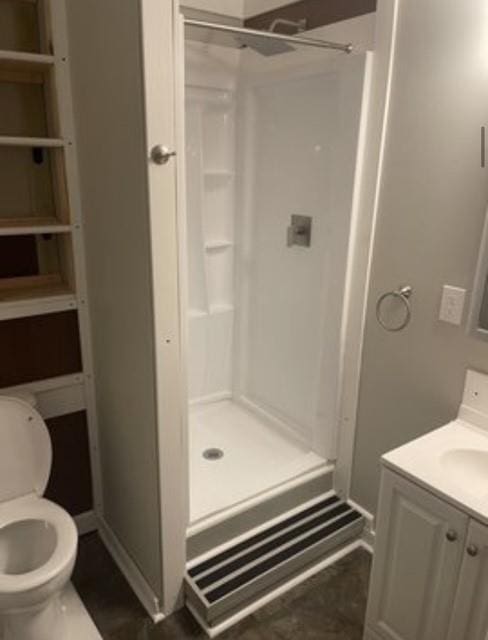 bathroom with walk in shower, vanity, and toilet