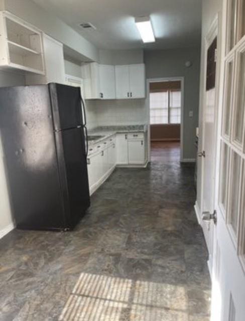 kitchen featuring black fridge and white cabinetry