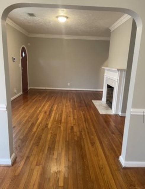 unfurnished living room featuring hardwood / wood-style flooring, ornamental molding, and a textured ceiling