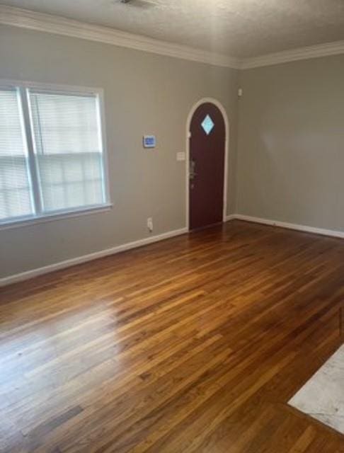 entryway with ornamental molding and dark wood-type flooring