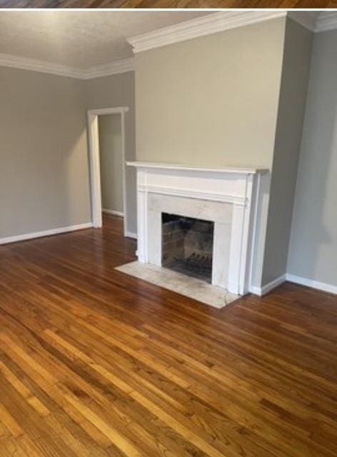 unfurnished living room featuring crown molding and dark wood-type flooring