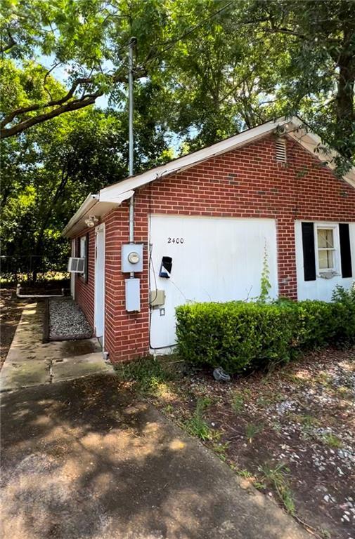 view of side of home with a garage, an outdoor structure, and cooling unit