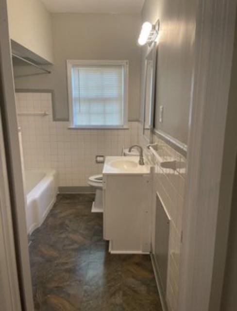 bathroom with vanity, a tub, tile walls, and toilet