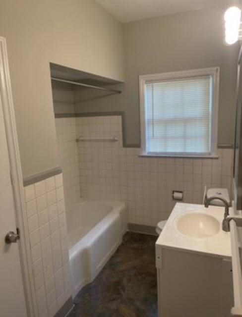 bathroom featuring vanity, toilet, a tub, and tile walls