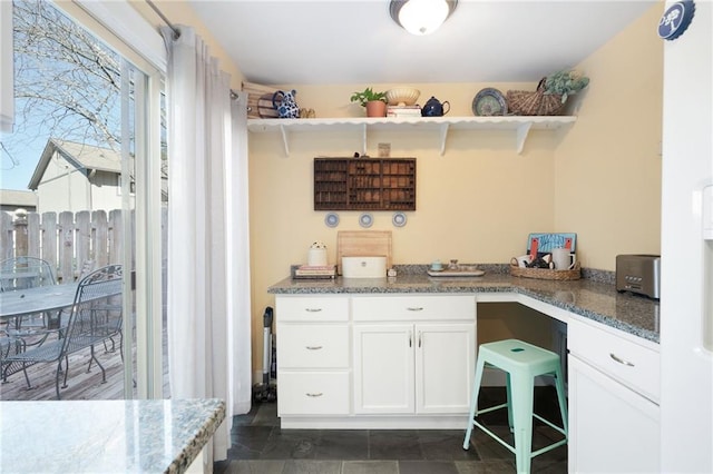 kitchen with white cabinetry and dark stone countertops