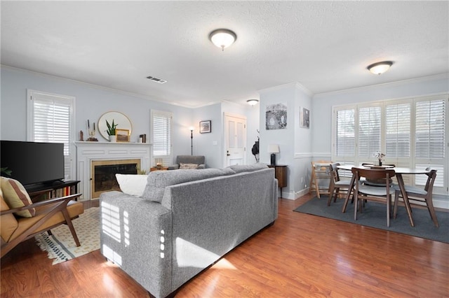 living room with a textured ceiling, a healthy amount of sunlight, wood-type flooring, and crown molding