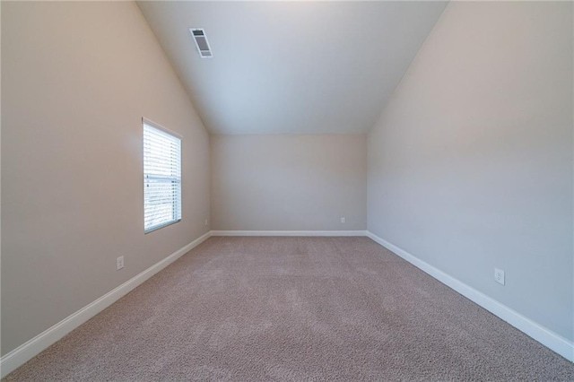 spare room featuring lofted ceiling and light carpet