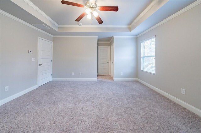 carpeted empty room featuring ceiling fan, a raised ceiling, and crown molding