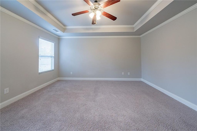 empty room featuring a raised ceiling, crown molding, and carpet