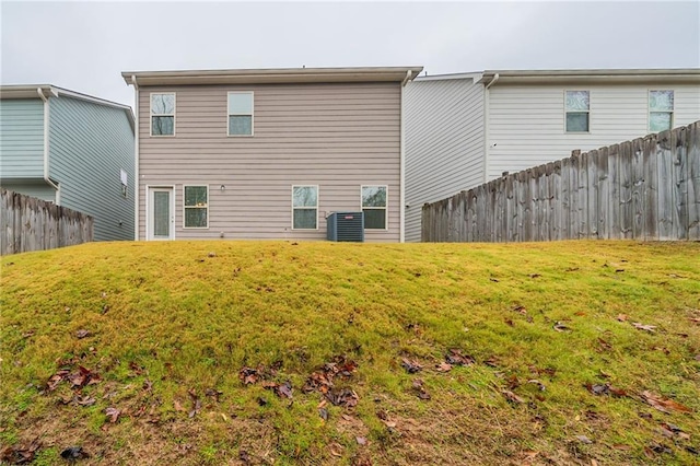 rear view of house featuring central AC unit and a lawn