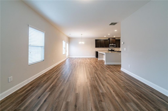 unfurnished living room featuring dark wood-type flooring and a notable chandelier