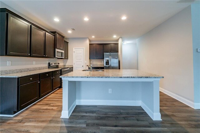 kitchen with appliances with stainless steel finishes, an island with sink, dark hardwood / wood-style floors, and sink