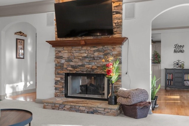 interior details featuring hardwood / wood-style flooring, ornamental molding, and a stone fireplace