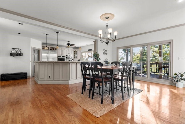 dining room featuring ornamental molding, ceiling fan with notable chandelier, and light wood-type flooring