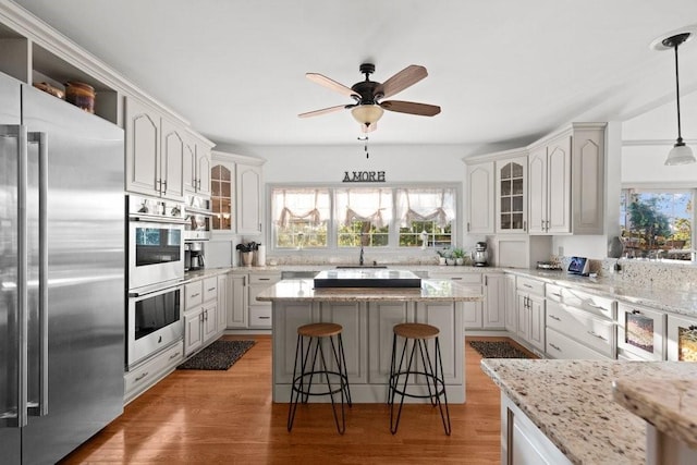 kitchen featuring white cabinetry, decorative light fixtures, a kitchen breakfast bar, a kitchen island, and stainless steel appliances