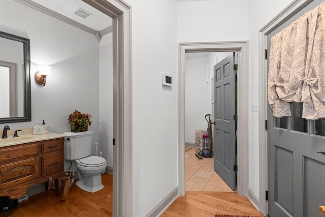 bathroom with hardwood / wood-style flooring, ornamental molding, vanity, and toilet