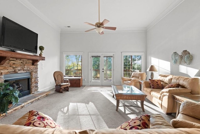 carpeted living room featuring crown molding, a stone fireplace, plenty of natural light, and french doors