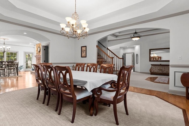 dining room featuring crown molding, light hardwood / wood-style floors, a raised ceiling, and a chandelier