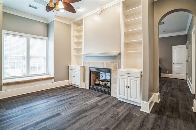 unfurnished living room featuring a tile fireplace, dark hardwood / wood-style floors, ceiling fan, and crown molding