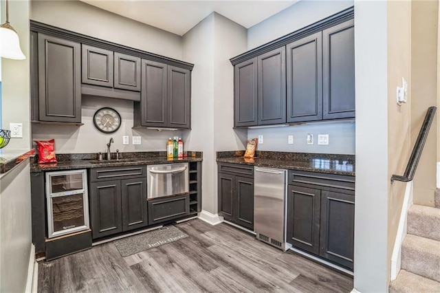 kitchen featuring hanging light fixtures, hardwood / wood-style flooring, sink, and dark stone counters