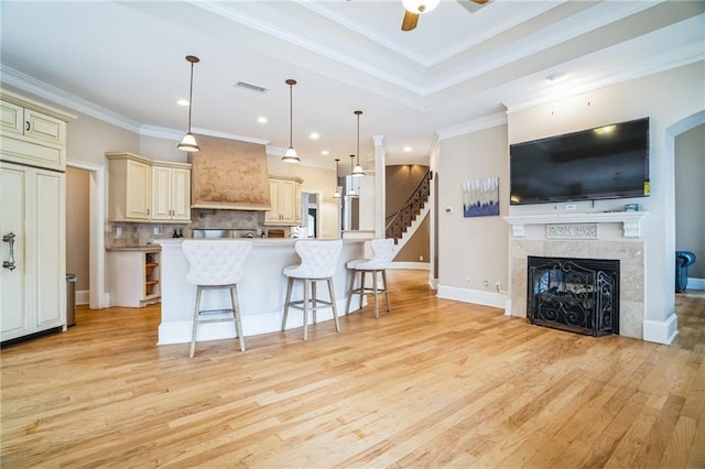 kitchen with a breakfast bar, ceiling fan, backsplash, hanging light fixtures, and cream cabinets