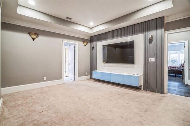 unfurnished living room with a raised ceiling, crown molding, and carpet floors