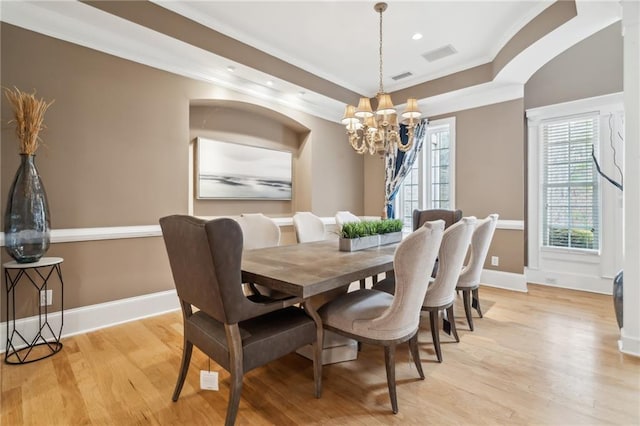 dining area featuring a notable chandelier, ornamental molding, and light wood-type flooring