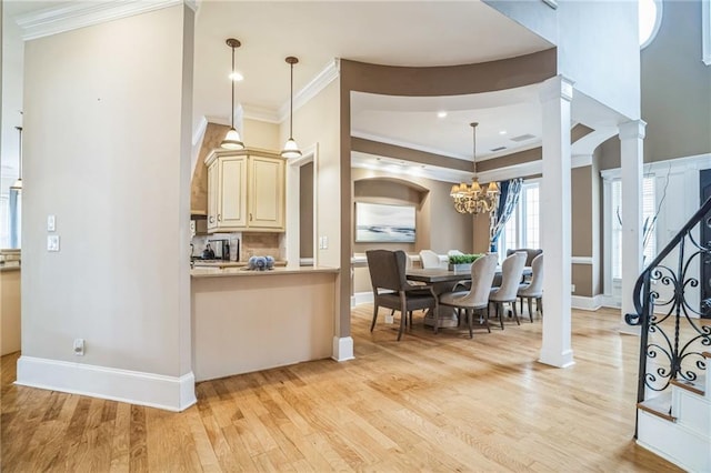 kitchen with pendant lighting, an inviting chandelier, decorative columns, cream cabinets, and light hardwood / wood-style floors