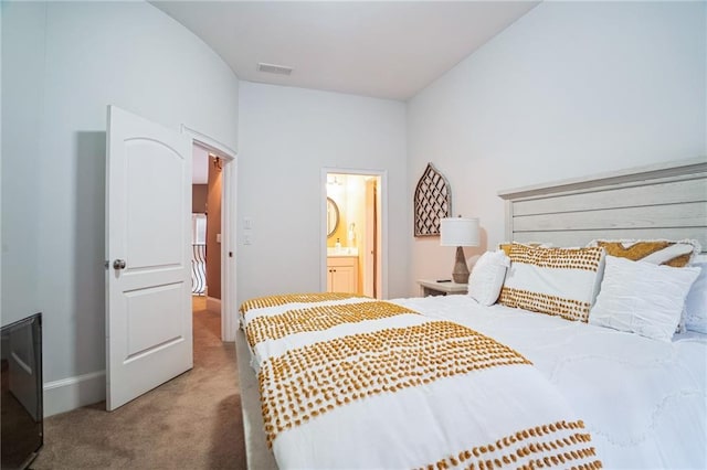 bedroom with connected bathroom, vaulted ceiling, and carpet flooring