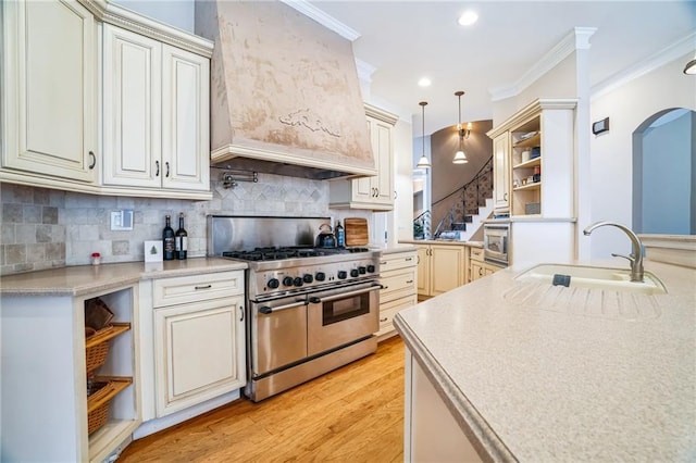 kitchen with sink, hanging light fixtures, stainless steel appliances, crown molding, and custom range hood