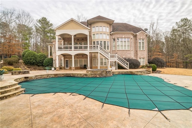 back of house featuring a pool with hot tub, a patio, and a balcony